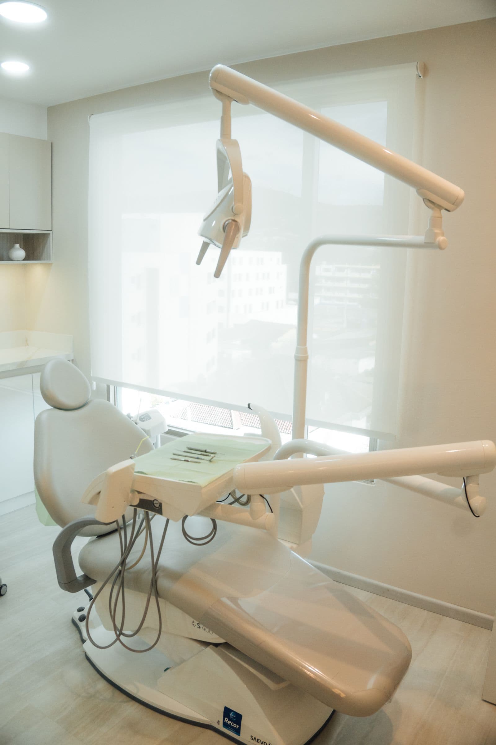 A bright, empty dental treatment room with a reclined chair and overhead light, nobody in it.